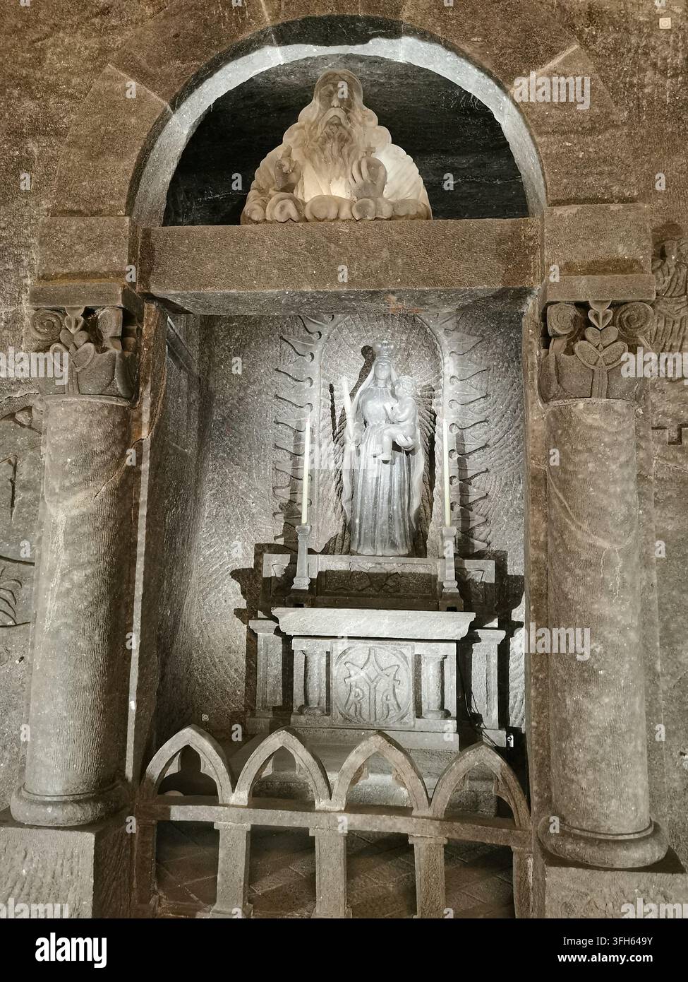 WIELICZKA, POLEN - 16. SEPTEMBER 2022: Ein geschnitzter Steinsalzschrein stellt Gott den Vater über einer Statue der Madonna mit Kind dar Stockfoto