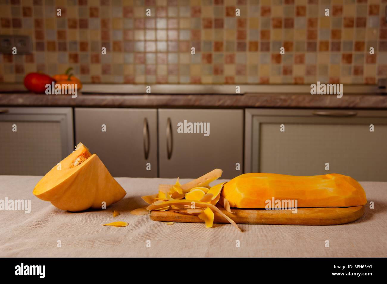 Geschälter Butternusskürbis mit Orangenresten auf Holzbrett, vorbereitet für das Herbstbacken Stockfoto