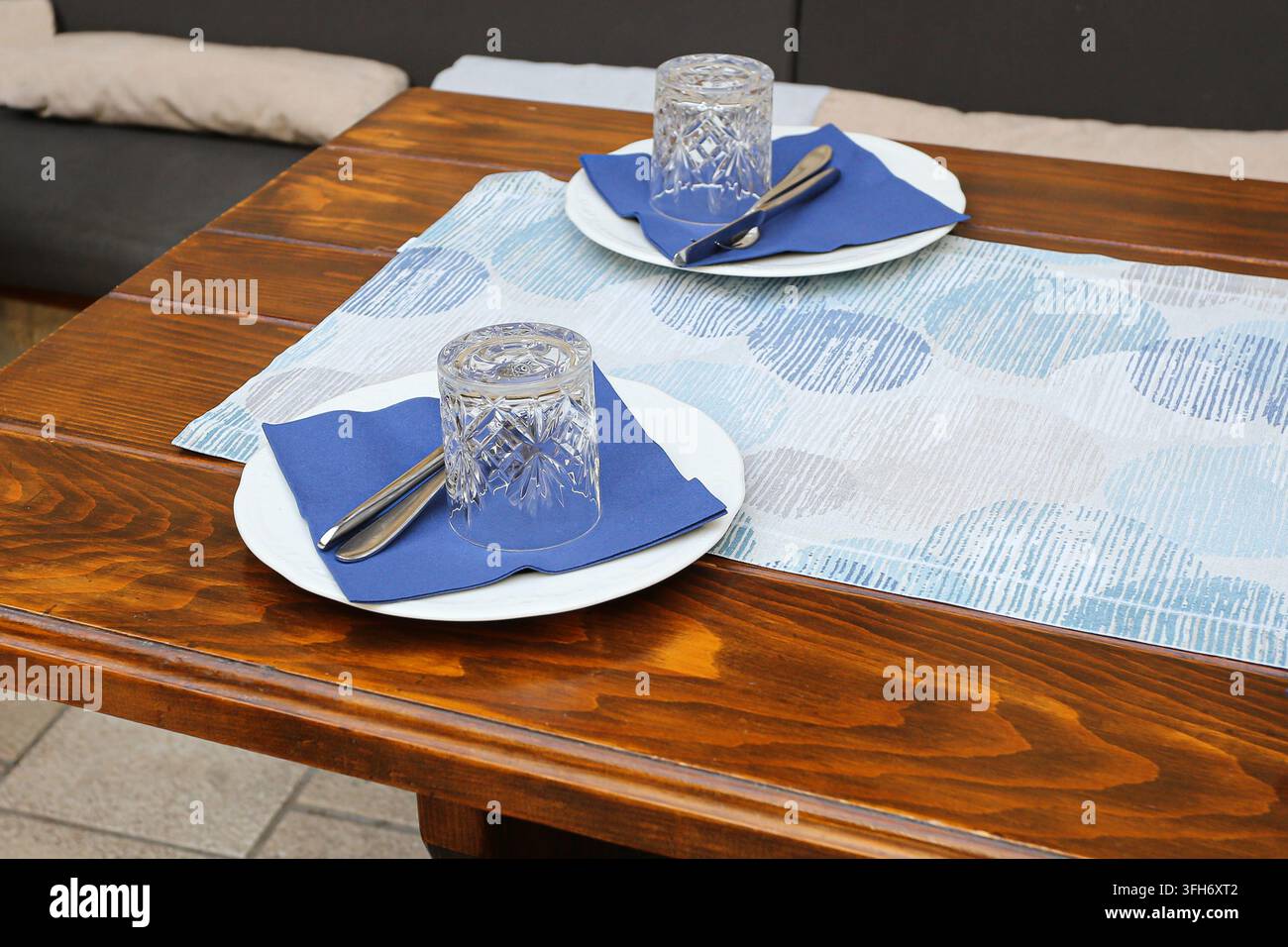 Esstisch gedeckt mit Tellern, Gläsern und Besteck für zwei Personen. Hintergrund für das Esszimmer zu Hause für die Mahlzeitvorbereitung, Tischgedeck, Abendessen und Gastfreundschaft. Stockfoto