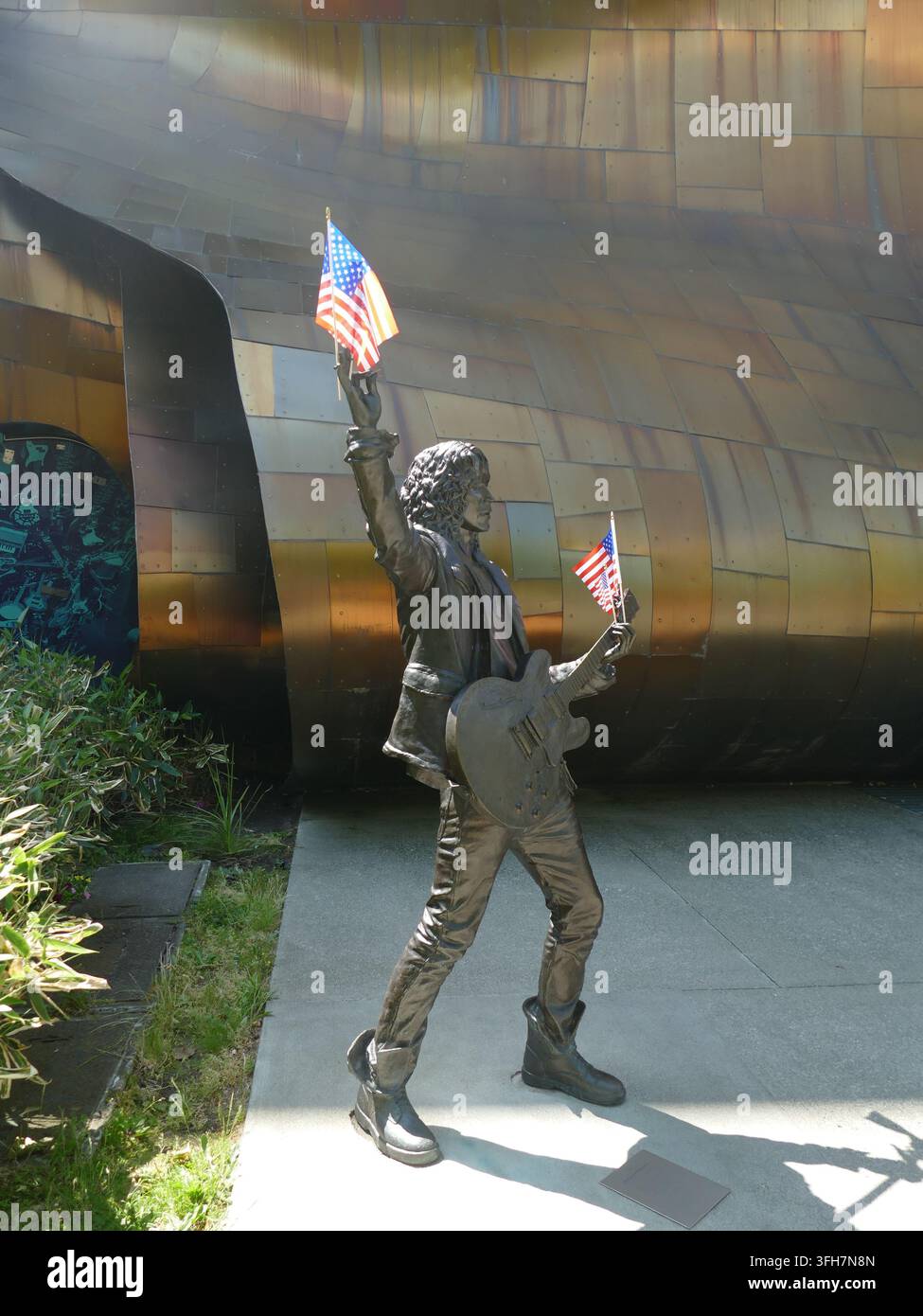 SEATTLE - 14. JUN 2025 - Bronzestatue von Jimi Hendrix mit zwei kleinen amerikanischen Flaggen vor dem MoPOP, entworfen von Frank Gehry, in Seattle. , Stockfoto