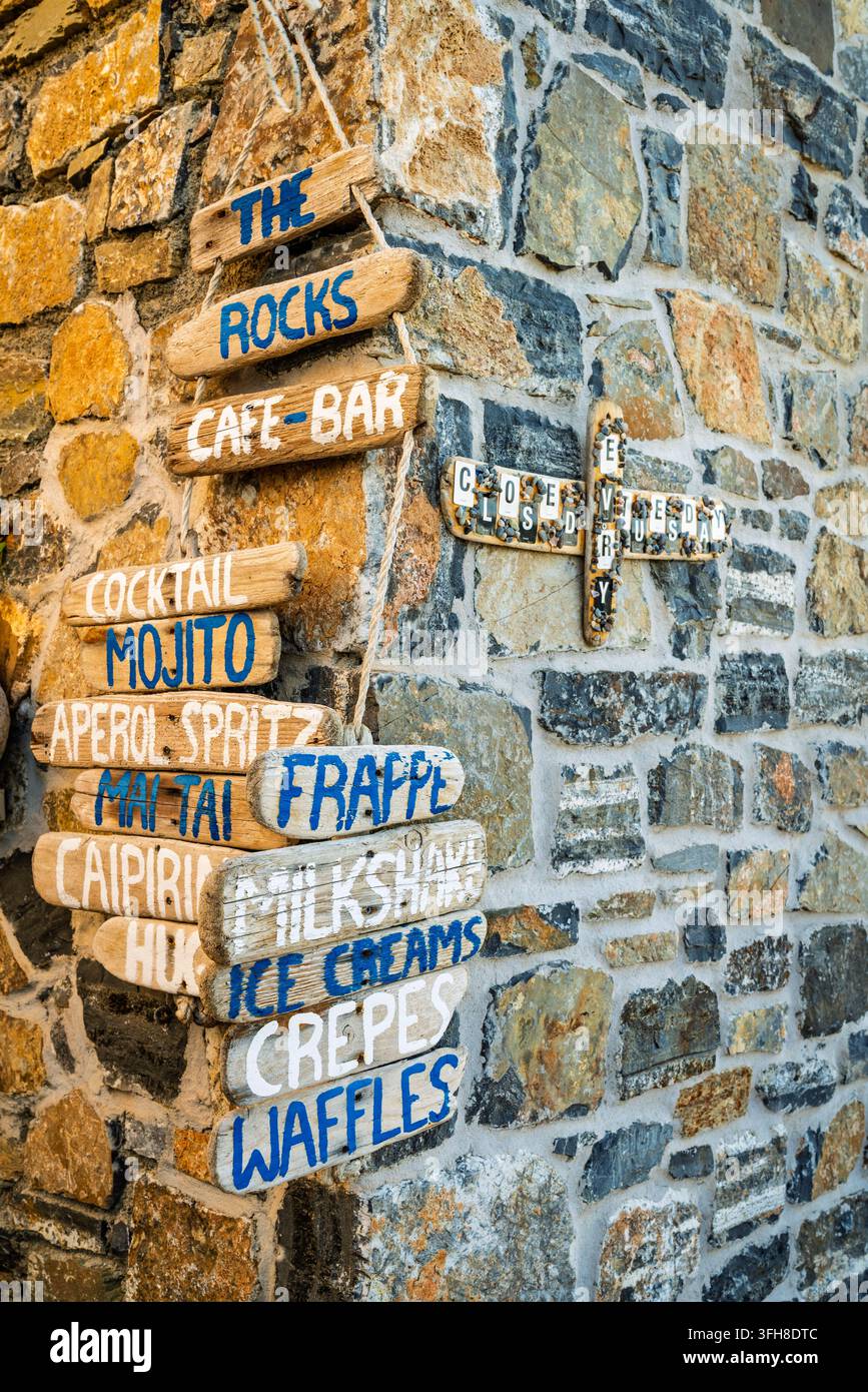 28. Juni 2022, Kreta, Griechenland: Rustikale Holzmenüschilder an einer Steinmauer, Mochlos, Kreta, Griechenland Stockfoto