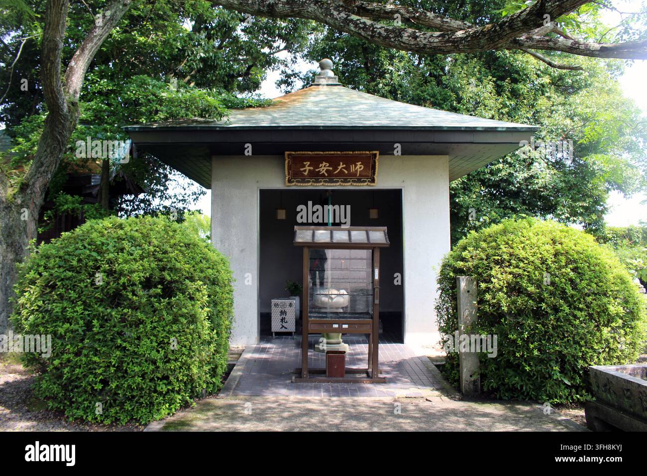 Der Pavillon des Koyasu-Daishi-Schreins in Koon-ji verfügt über eine steinerne Nische, die eine stehende Bronzestatue von Kobo Daishi beherbergt, die ein Kind hält, vor der ein hölzerner D steht Stockfoto