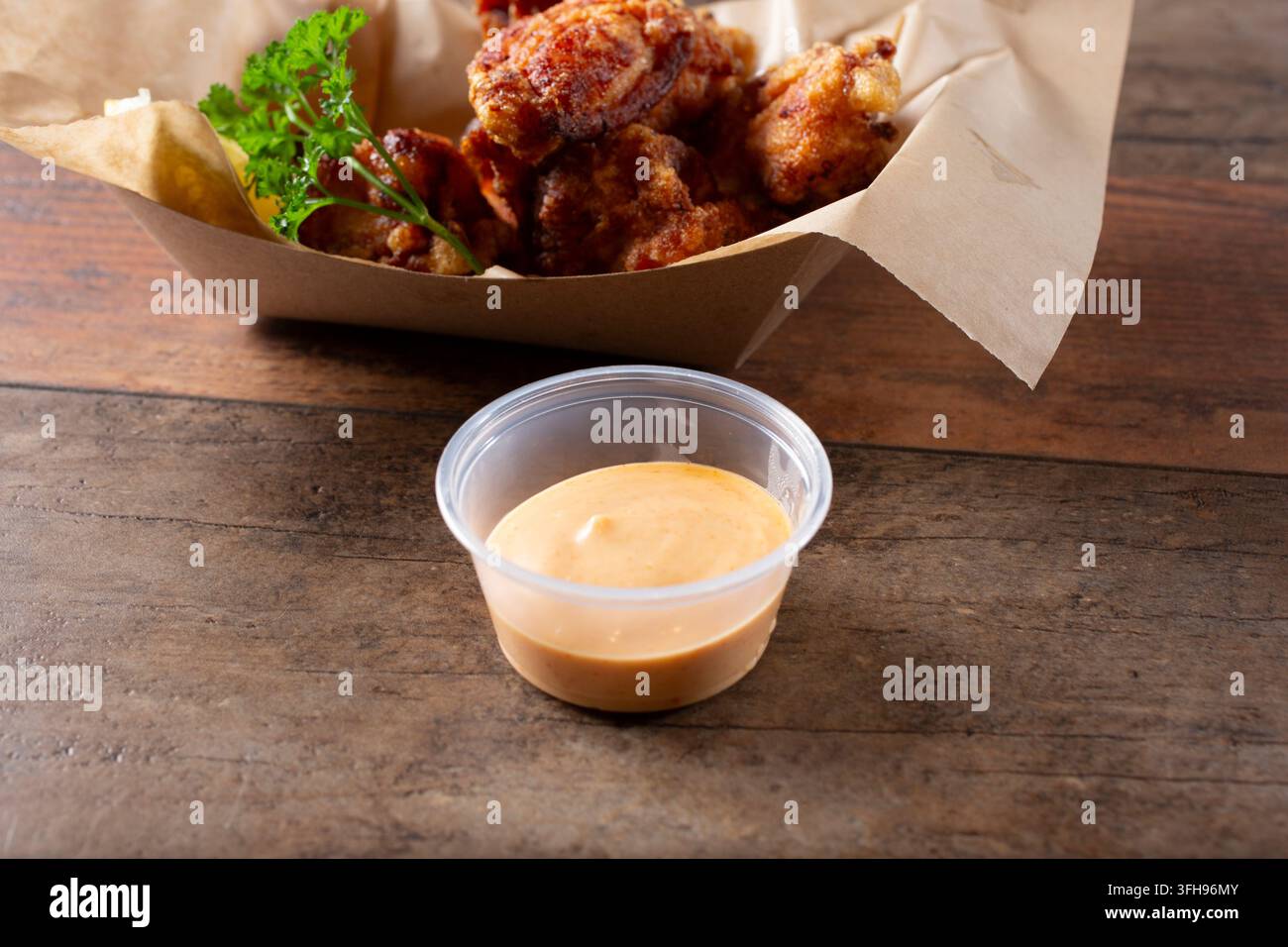 Eine Ansicht einer Plastik-Dressingschale mit Sriracha-Mayo-Sauce. Stockfoto