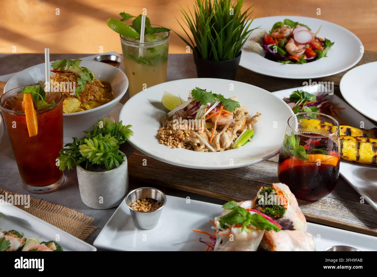 Eine Ansicht mehrerer thailändischer Gerichte auf einem Esstisch, darunter Pad Thai, Panang-Curry, Hähnchensatay, grünes Curry und Garnelen-Miang Kham. Stockfoto