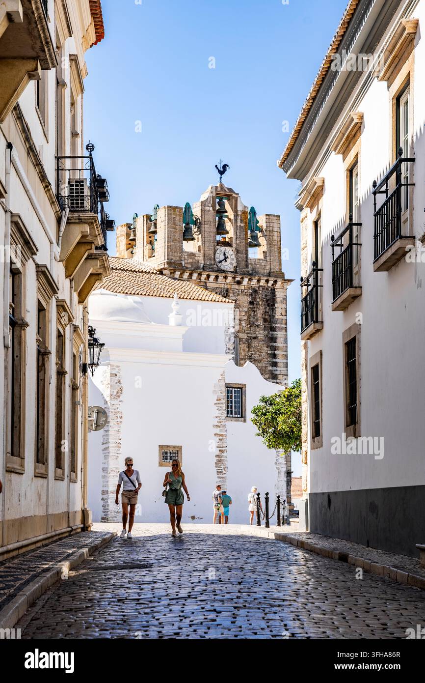 Rua do Municipio in der Altstadt von Faro, die zur Kathedrale führt, mit zwei Personen, die im historischen Stadtzentrum von Faro, Algarve, Portugal, spazieren gehen Stockfoto