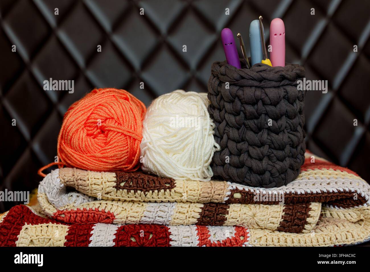 Handgefertigte Häkeldecke mit Garnknäueln und Häkeln. Häkelhobby für geistiges Wohlbefinden, digitale Entgiftung, Entspannung Stockfoto