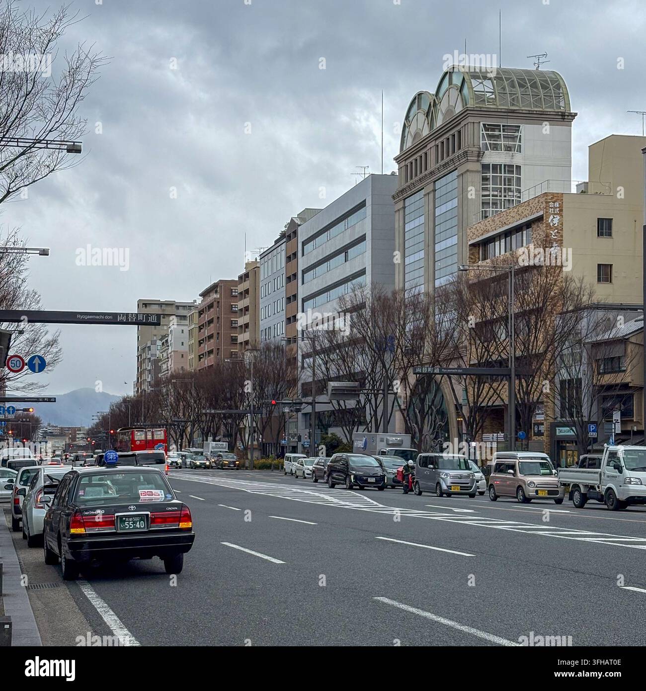 Tagesansicht einer städtischen Straße mit Stadtverkehr, der entlang einer Hauptstraße in Kyoto, Japan, fährt. - Smartphone-aufgenommenes Stockfoto