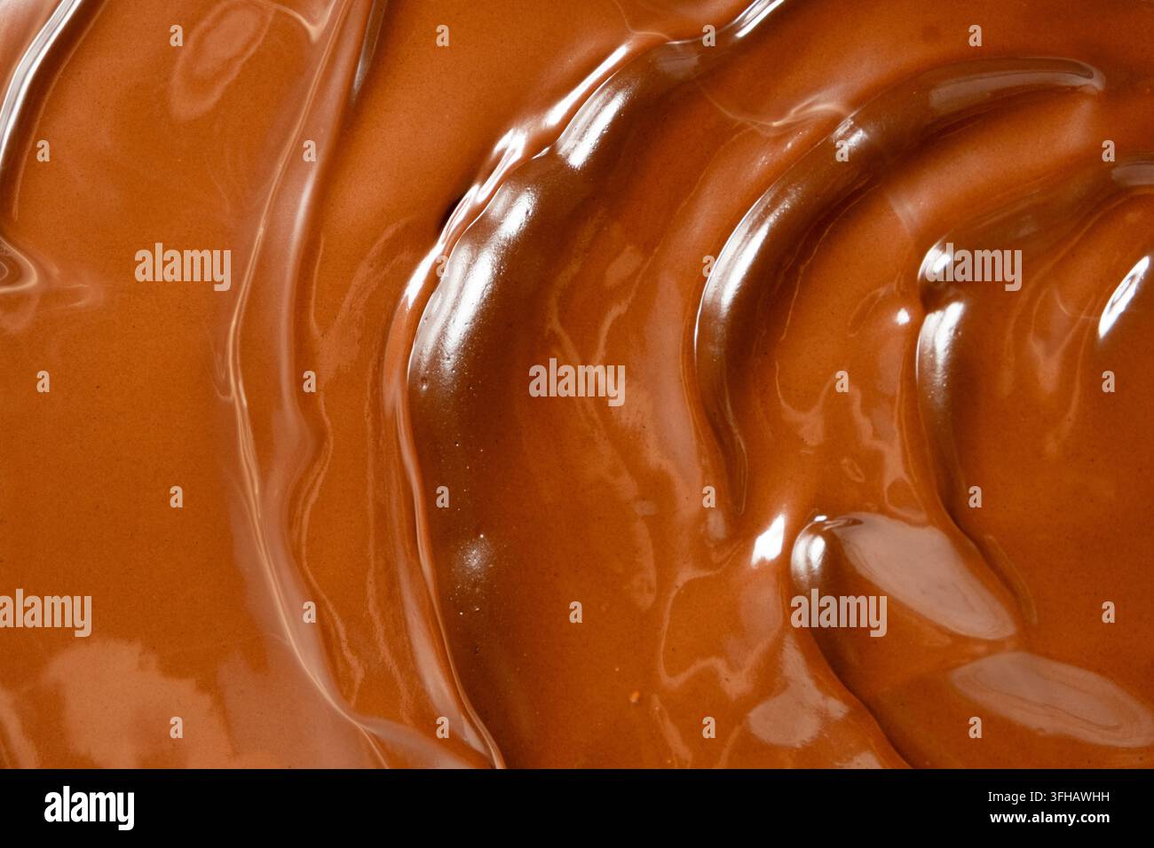 Wirbelnder geschmolzener Milchschokoladenhintergrund mit glänzender Wellenstruktur. Stockfoto