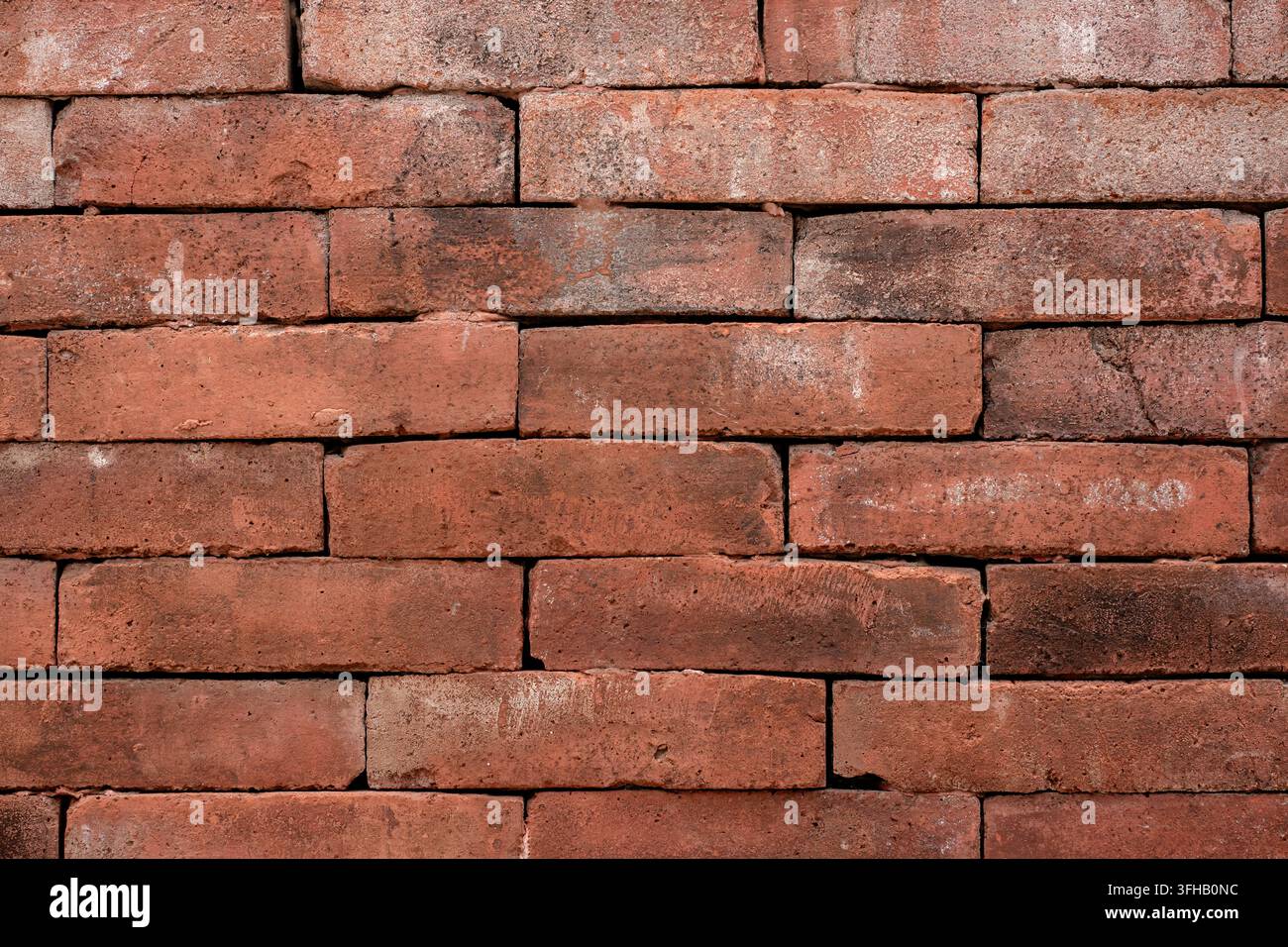 Vollbild-Hintergrundtextur einer traditionellen roten Ziegelwand mit natürlichen Farbvariationen und groben Mauerwerksdetails. Stockfoto