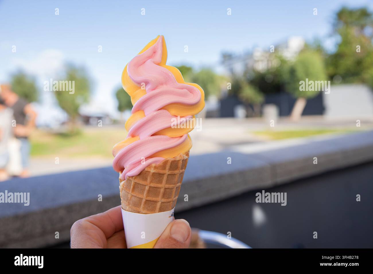 Rosa und orangefarbene Softeis, die im Sommer im Freien gehalten werden Stockfoto