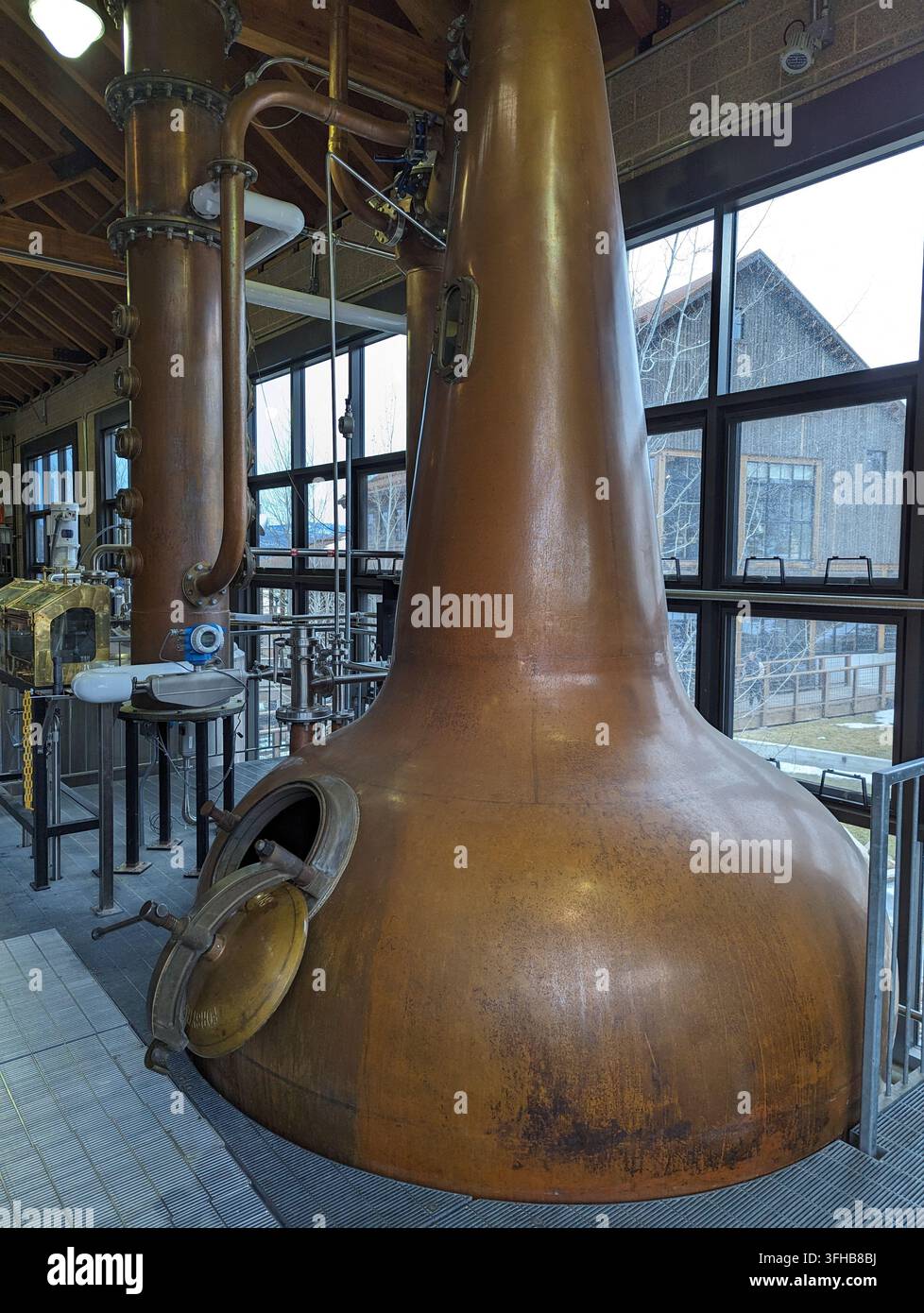 Innenraum einer Whiskey-Brennerei mit Kupferbrennblase und industriellen Geräten. Stockfoto