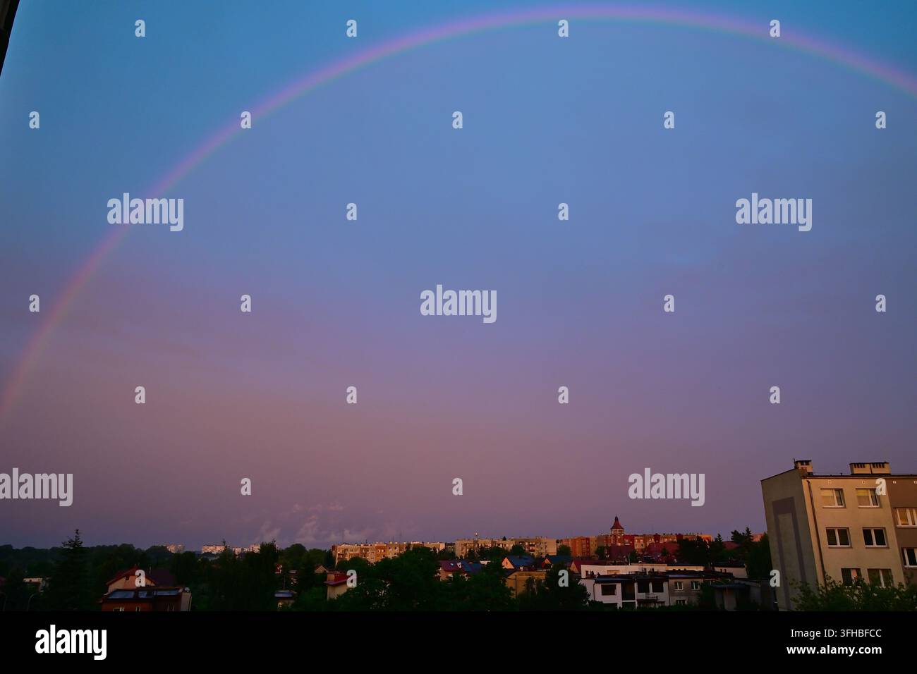 Pittoresker Regenbogen über dem Wohngebiet Polne in Lubin mit einem Wasserturm in der Ferne. Stockfoto
