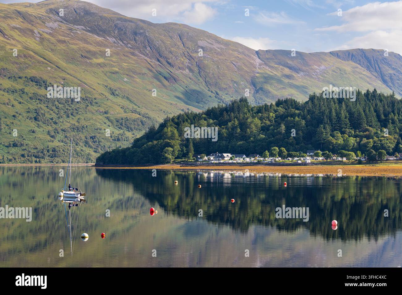Das Dorf Glencoe blickt an einem friedlichen Sommertag in den schottischen Highlands auf die ruhigen Gewässer von Loch Leven. Stockfoto