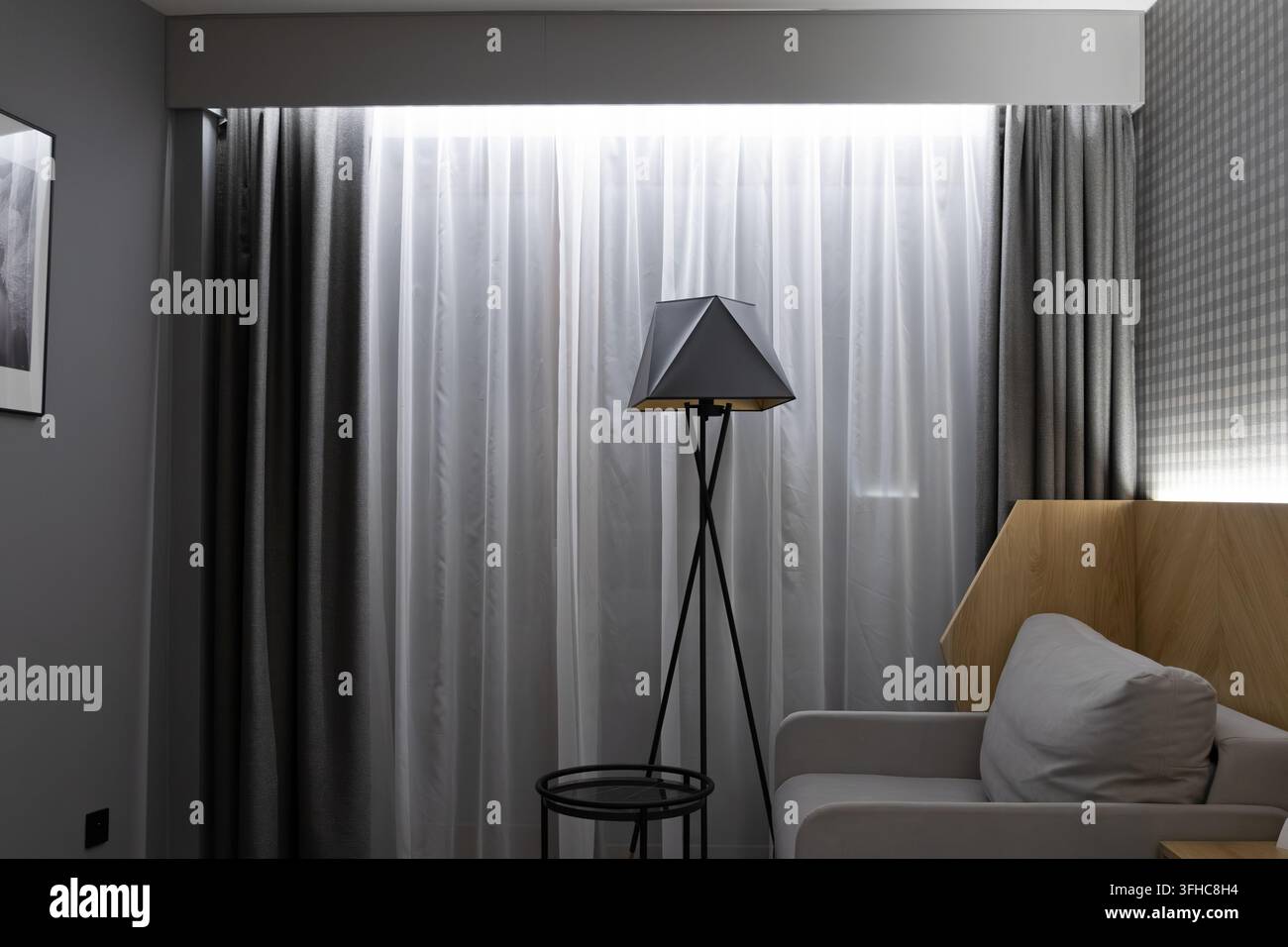 Minimalistisches Innendesign zeigt eine schlanke Dreibeinlampe neben einem eleganten Sitz, das eine ruhige und raffinierte Ästhetik bietet, die den Komfort erhöht Stockfoto