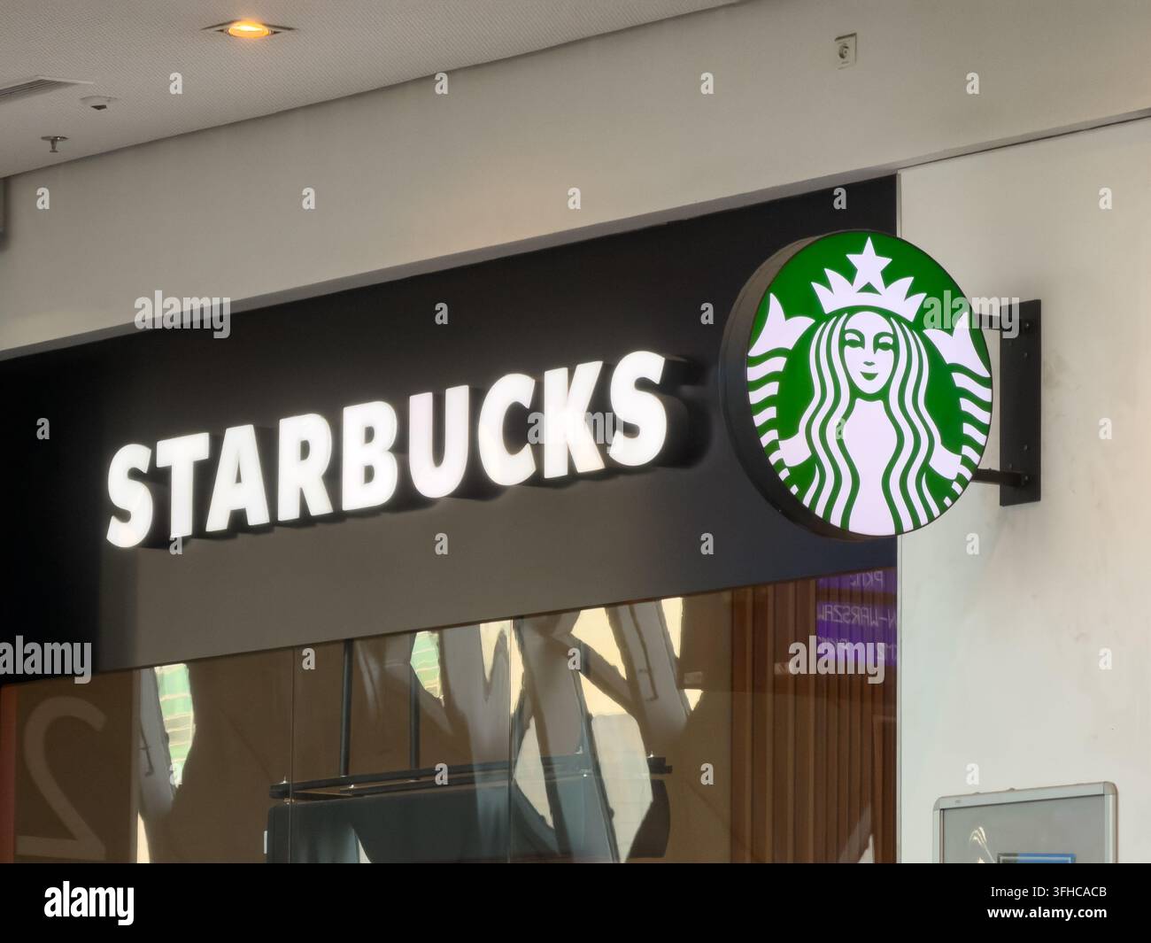 Posen, Polen – 15. Dezember 2025: Starbucks-Logo auf einer leuchtenden Außenwand eines Cafés, das Retailsdesign und die Unternehmensidentität hervorhebt Stockfoto