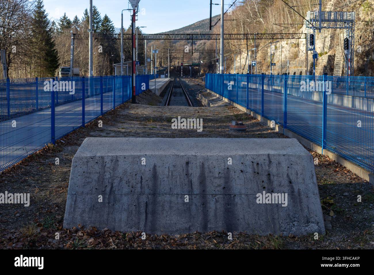 Ansicht einer einzelnen Transportbahn, die sich durch ein bergiges Gebiet windet, eingerahmt von neuen blauen Sicherheitszäunen, die Fortschritt und sicheren Durchgang darstellen Stockfoto