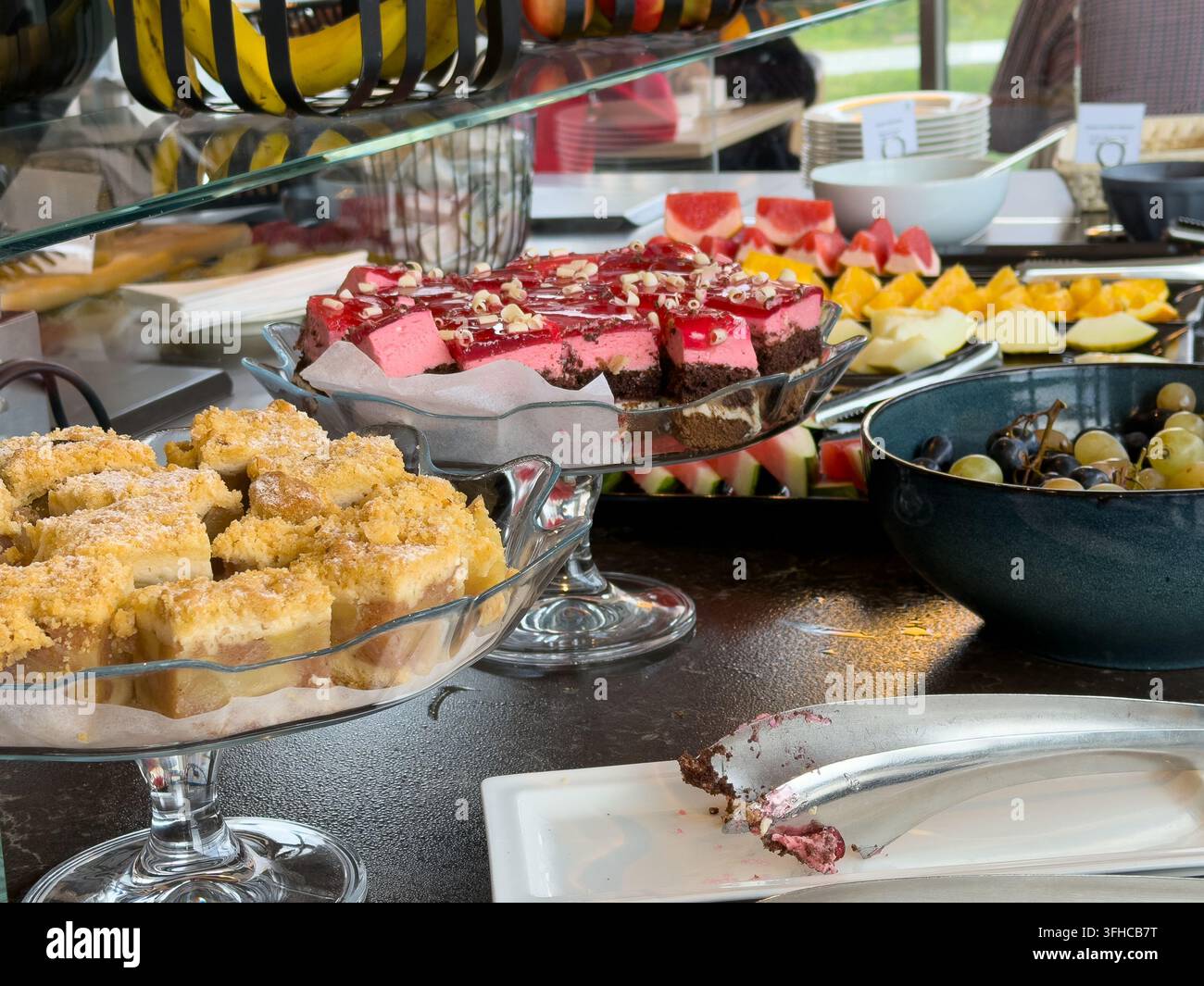Nahaufnahme einer vielfältigen und farbenfrohen Buffetauswahl, die Gourmetkuchen und verschiedene frisch geschnittene Früchte hervorhebt und köstliche Optionen für ein luxuriöses Stockfoto
