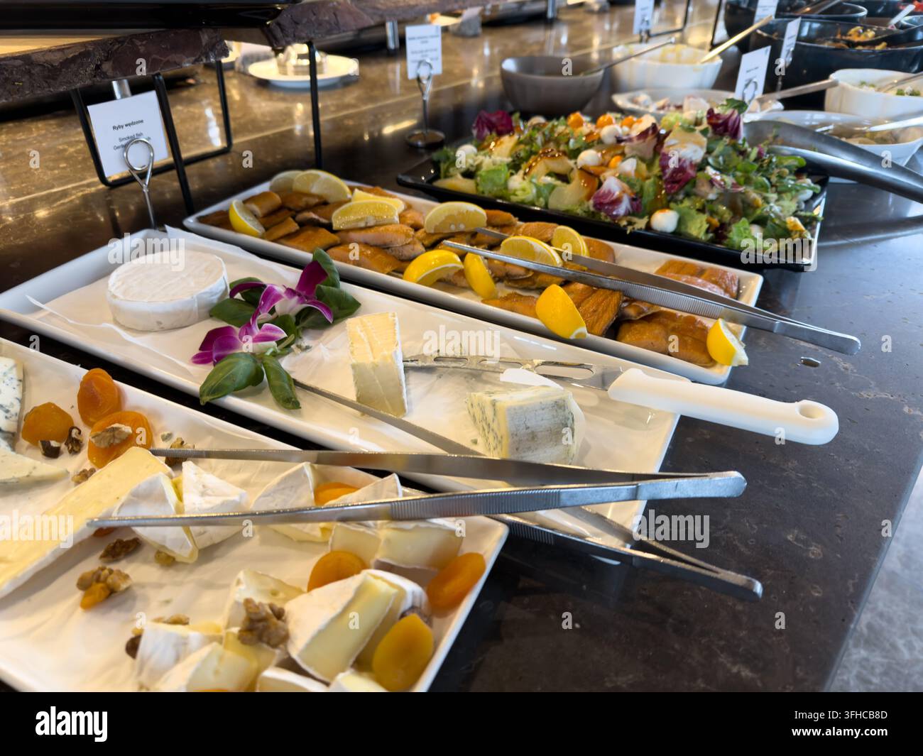 Top-Down-Ansicht eines anspruchsvollen Hotel-Buffets mit sorgfältig arrangierten Platten mit kunsthandwerklichem Käse, herzhaftem geräuchertem Fisch und einem farbenfrohen Knuspergratin Stockfoto