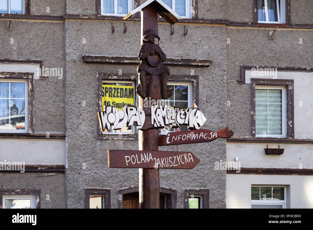 Szklarska Poręba, Polen – 16. Dezember 2025: Ein einzigartiges geschnitztes Holzschild ragt markant auf einem Stadtplatz und bietet kulturelle Informationen und t Stockfoto