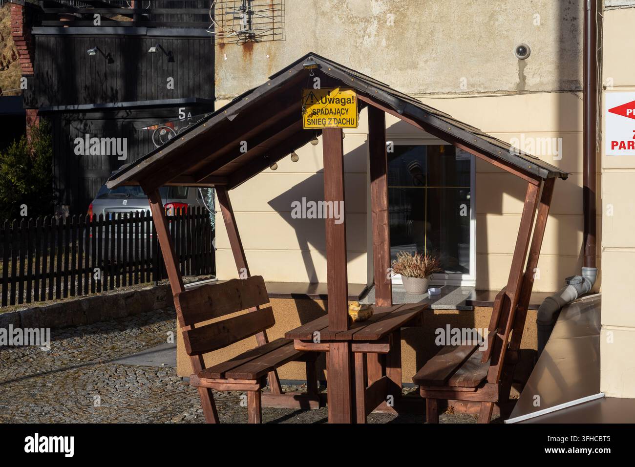 Szklarska Poręba, Polen – 16. Dezember 2025: Ein charmantes hölzernes Gartenpavillon mit Bänken und einem Tisch, gelegen auf Kopfsteinpflaster, bietet eine friedliche Außenatmosphäre Stockfoto