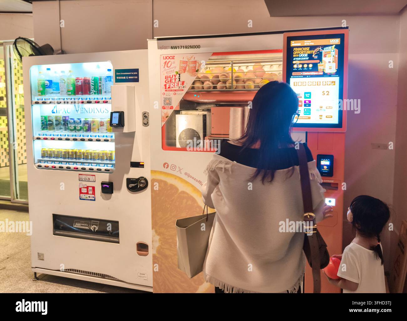 Ein Kunde an einem automatisierten Selbstbedienungs-Automaten von iJooz mit einem digitalen Touchscreen-Interface, Singapur Stockfoto
