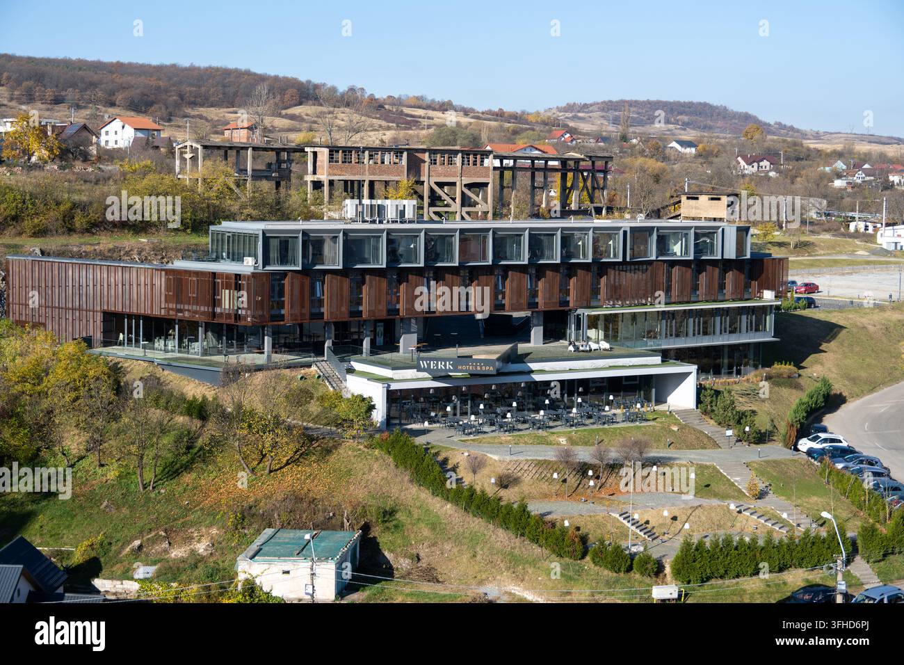 Hunedoara, Rumänien - 5. Nov 25: Blick vom Corvin-Schloss auf ein modernes Hotel- und Spa-Gebäude in Hunedoara, Rumänien, vor Herbsthügeln. Stockfoto