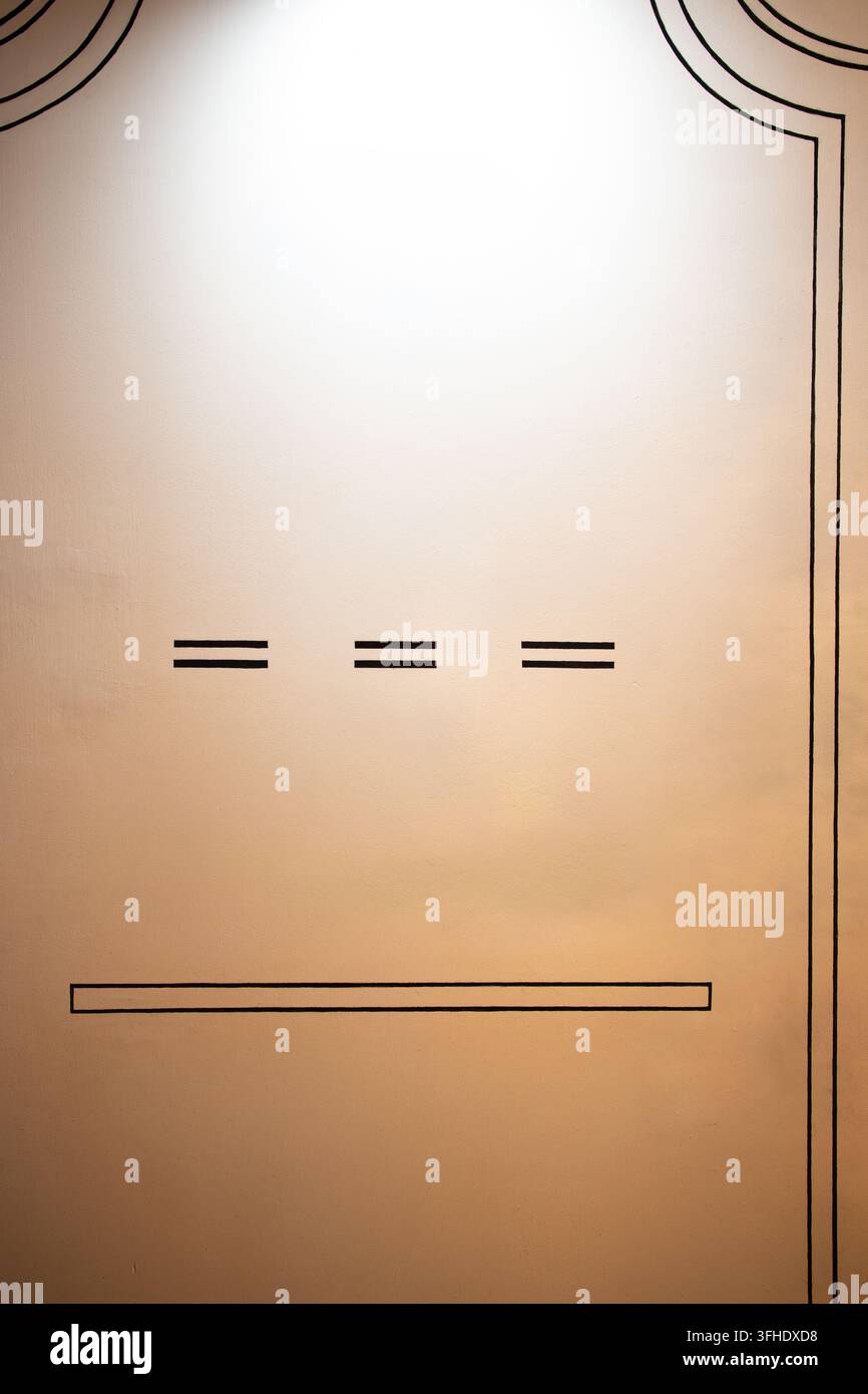 Eine vertikale Innenaufnahme einer glatten, warmtönigen Wand mit minimalistischer schwarzer Linienkunst. Ein gebogener Rahmen ziert die obere Kante, begleitet von Stockfoto