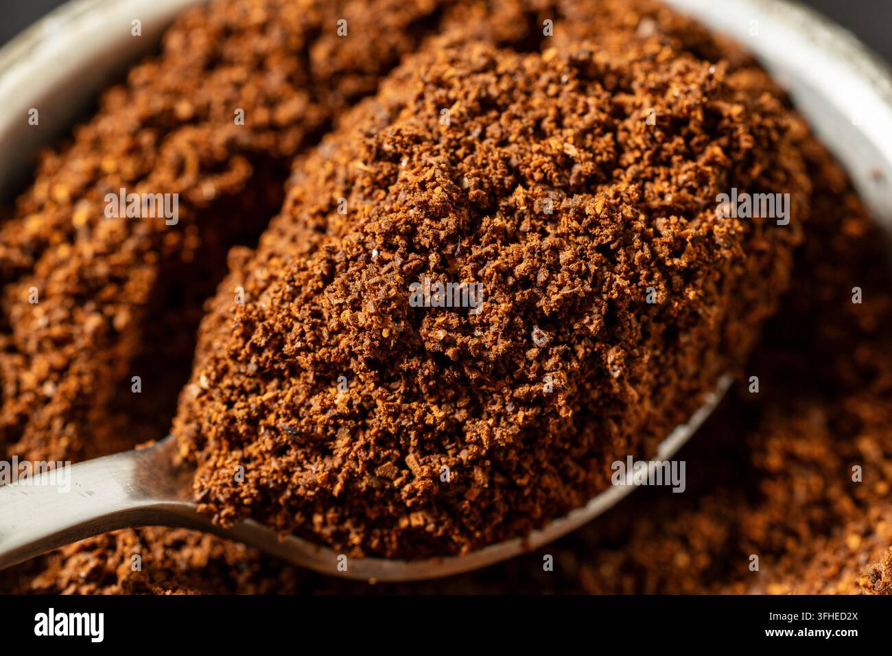 Gemahlener Kaffee auf einem Löffel, Nahaufnahme von frisch gemahlenem geröstetem Kaffee mit reichhaltiger brauner Textur, aromatischer Bestandteil für die Zubereitung von Heißgetränken Stockfoto