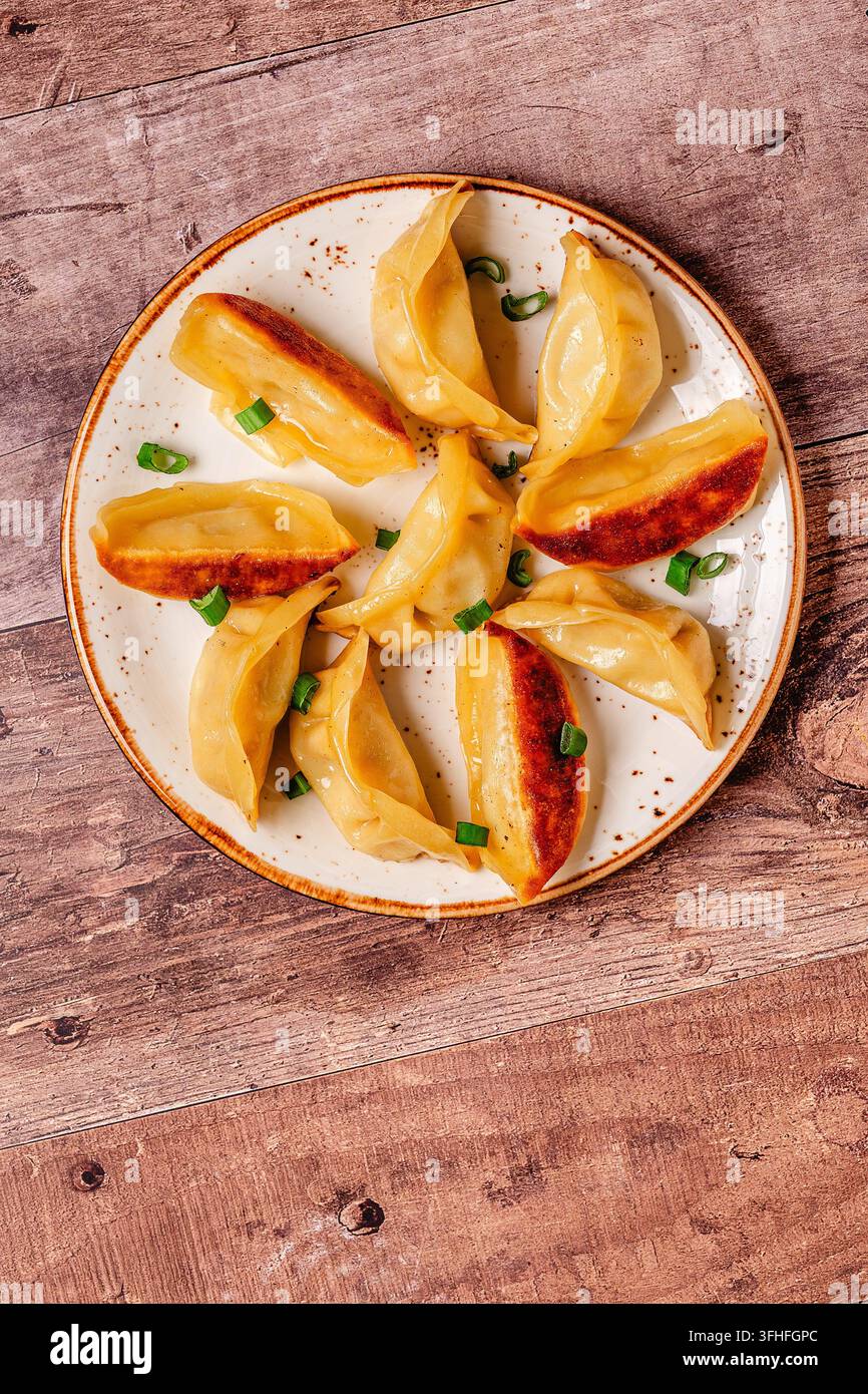Knödel auf einem Teller mit grünen Zwiebeln in einer einfachen Kücheneinrichtung während des Mittagessens Stockfoto