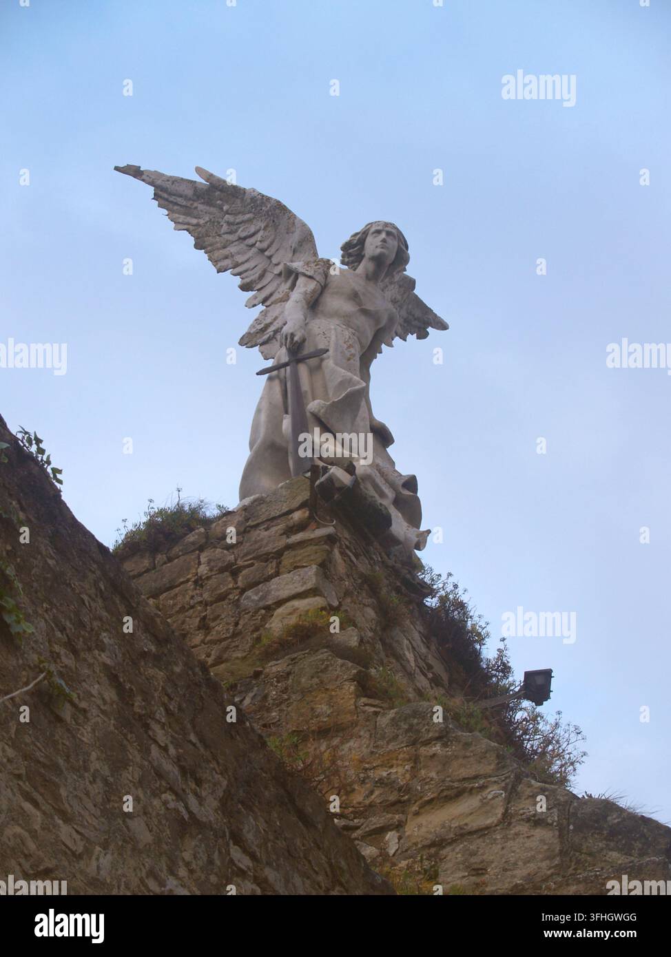 Statue des Exterminationsengels von Josep Limona im gotischen Friedhof von Comillas, Kantabrien. Modernistische Skulptur auf einer Steinmauer unter einem blauen Himmel Stockfoto