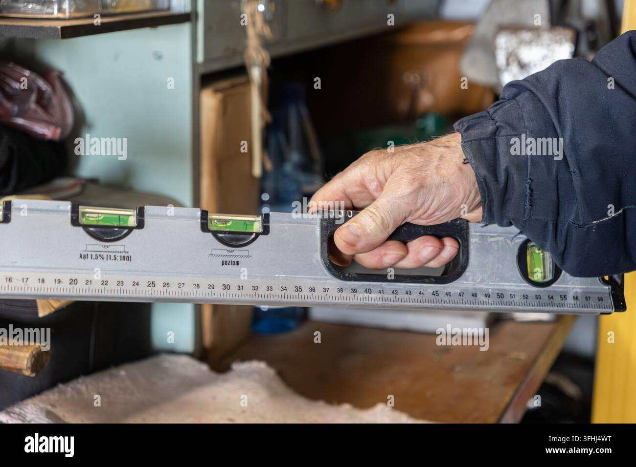 Ein erfahrener Bauarbeiter verwendet eine Wasserwaage, um die genaue horizontale Ausrichtung sicherzustellen, und demonstriert professionelle Handwerkskunst und Atten Stockfoto