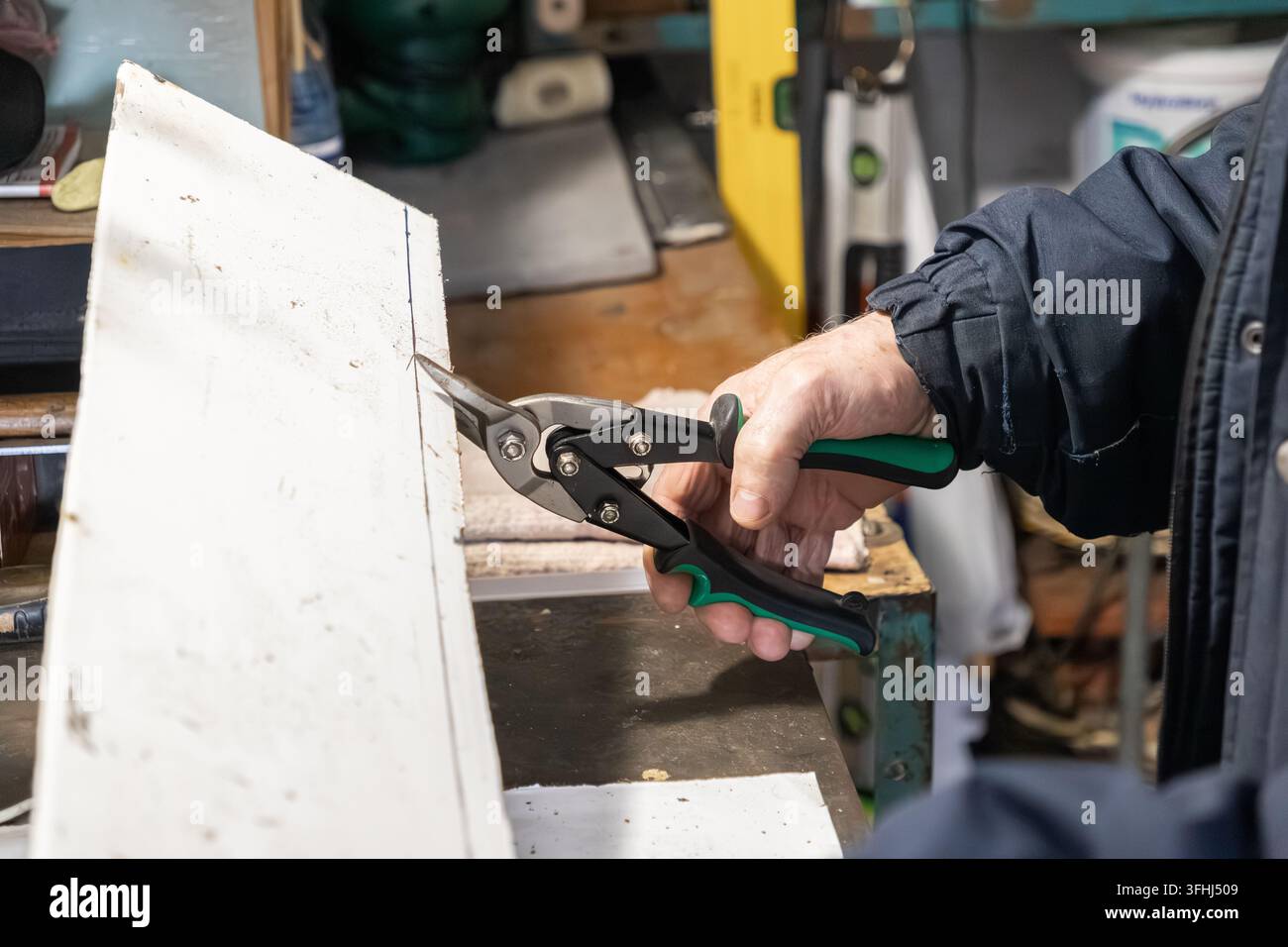 Techniker verwendetLuftschneiderschere, um ein weißes Gebäudeblatt zu schneiden, was industrielle Wartung, Konstruktionsexpertise und zuverlässige Handarbeit widerspiegelt i Stockfoto