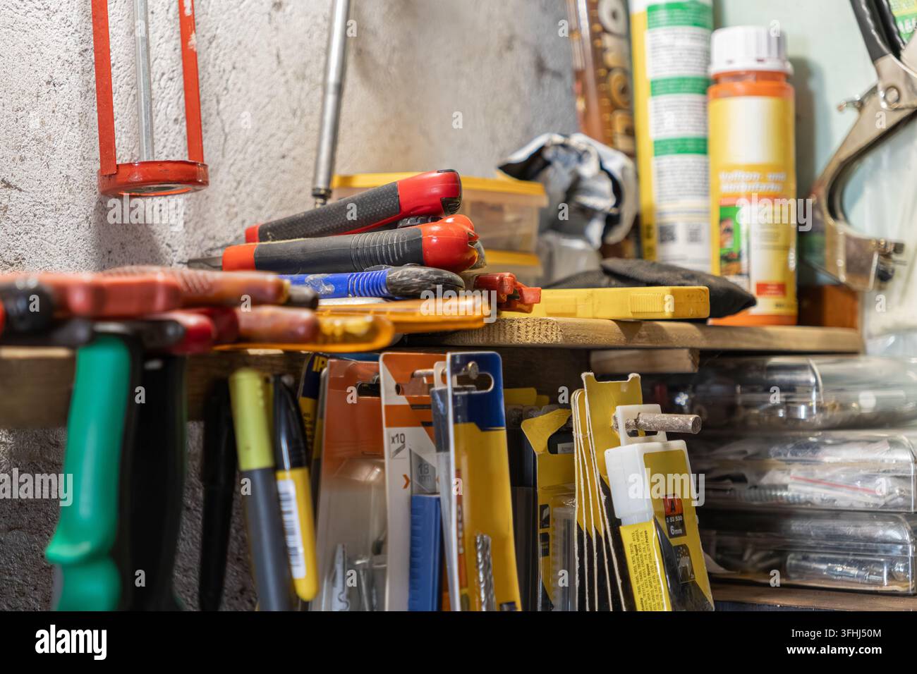 Verschiedene professionelle Werkzeuge und Baumaterialien ordentlich auf einem Garagenregal gelagert, die eine effektive Arbeitsplatzvorbereitung für Wohnbereiche veranschaulichen Stockfoto