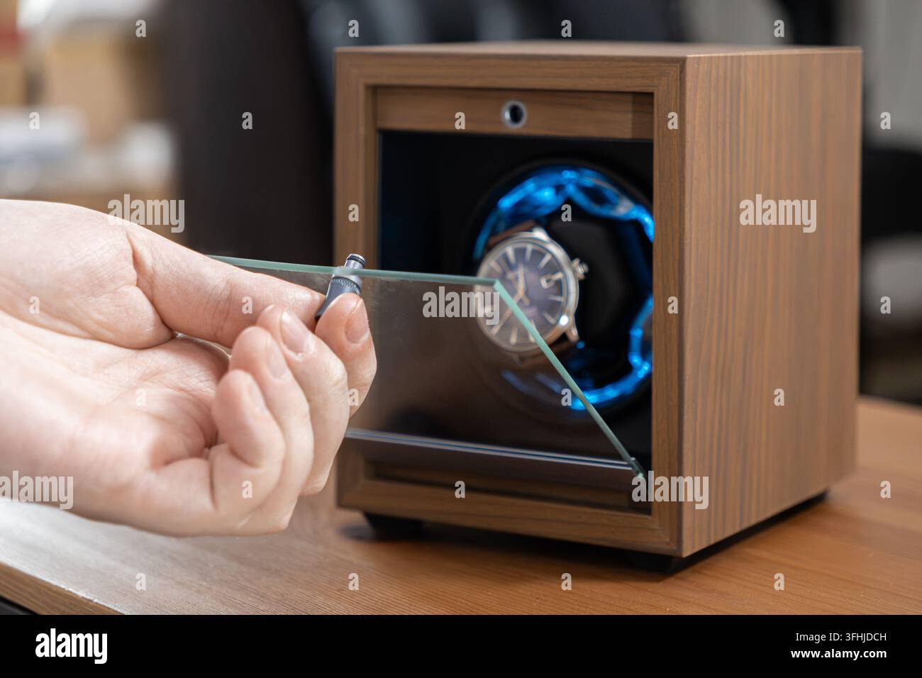 Ein automatischer mechanischer Uhrenaufzug hält ein raffiniertes Accessoire, während er von blauem Licht beleuchtet wird, und zeigt organisierte Schutz und Prem Stockfoto