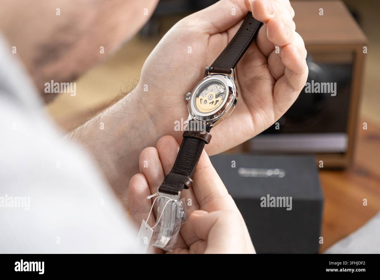 Ein Enthusiast inspiziert eine hochwertige Armbanduhr mit sichtbarem Werk und demonstriert präzise Technik und qualitativ hochwertiges Design in einem Sophistikat Stockfoto