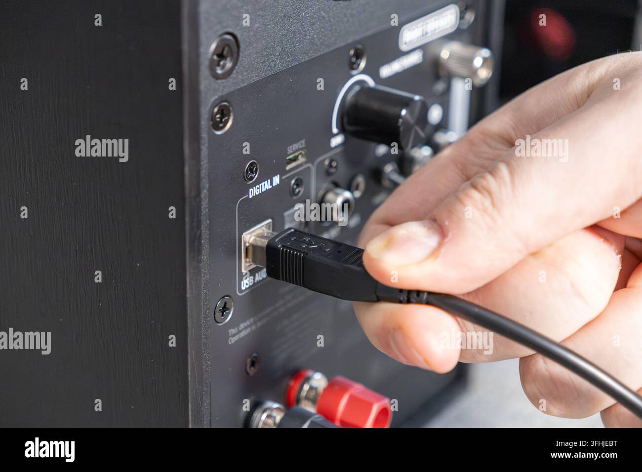 Nahaufnahme von Fingern, die einen digitalen Anschluss in die Rückseite eines Hoch Fidelity-Lautsprechers stecken, um eine Verbindung für Musikproduktion und Gaming herzustellen Stockfoto