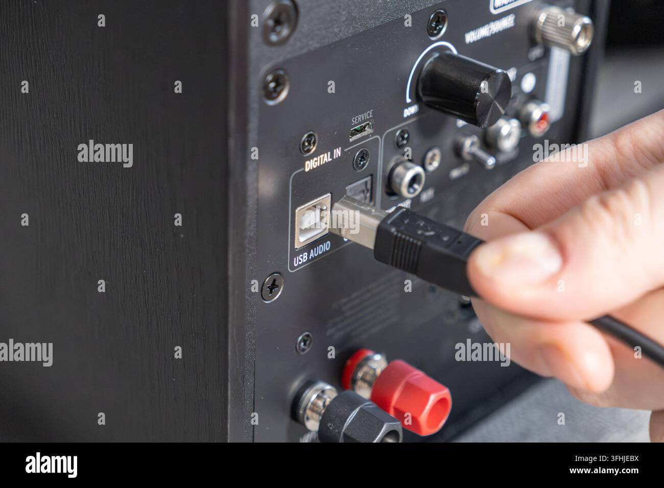 Nahaufnahme einer Person, die einen Stecker an eine Lautsprecher-Schnittstelle anschließt, um Musik-Hardware zu aktivieren, was technische Installation, Multimedia-Produktion und Stockfoto