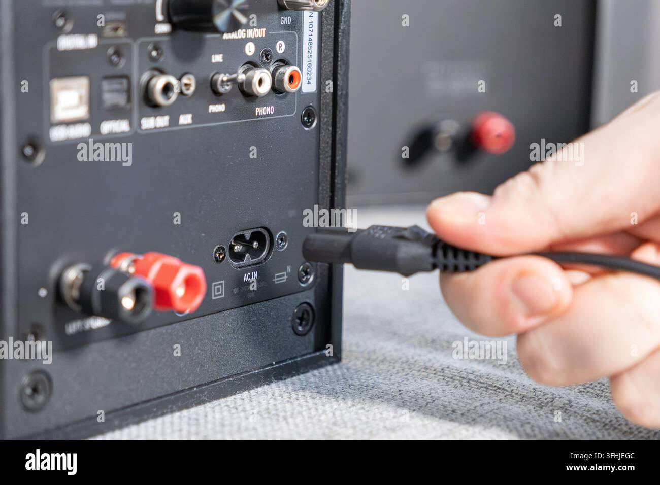Nahaufnahme eines elektrischen Kabels, das an einen Studiomonitor-Lautsprecher angeschlossen wird, und veranschaulicht die einfache Installation einer professionellen Heimunterhaltung Stockfoto