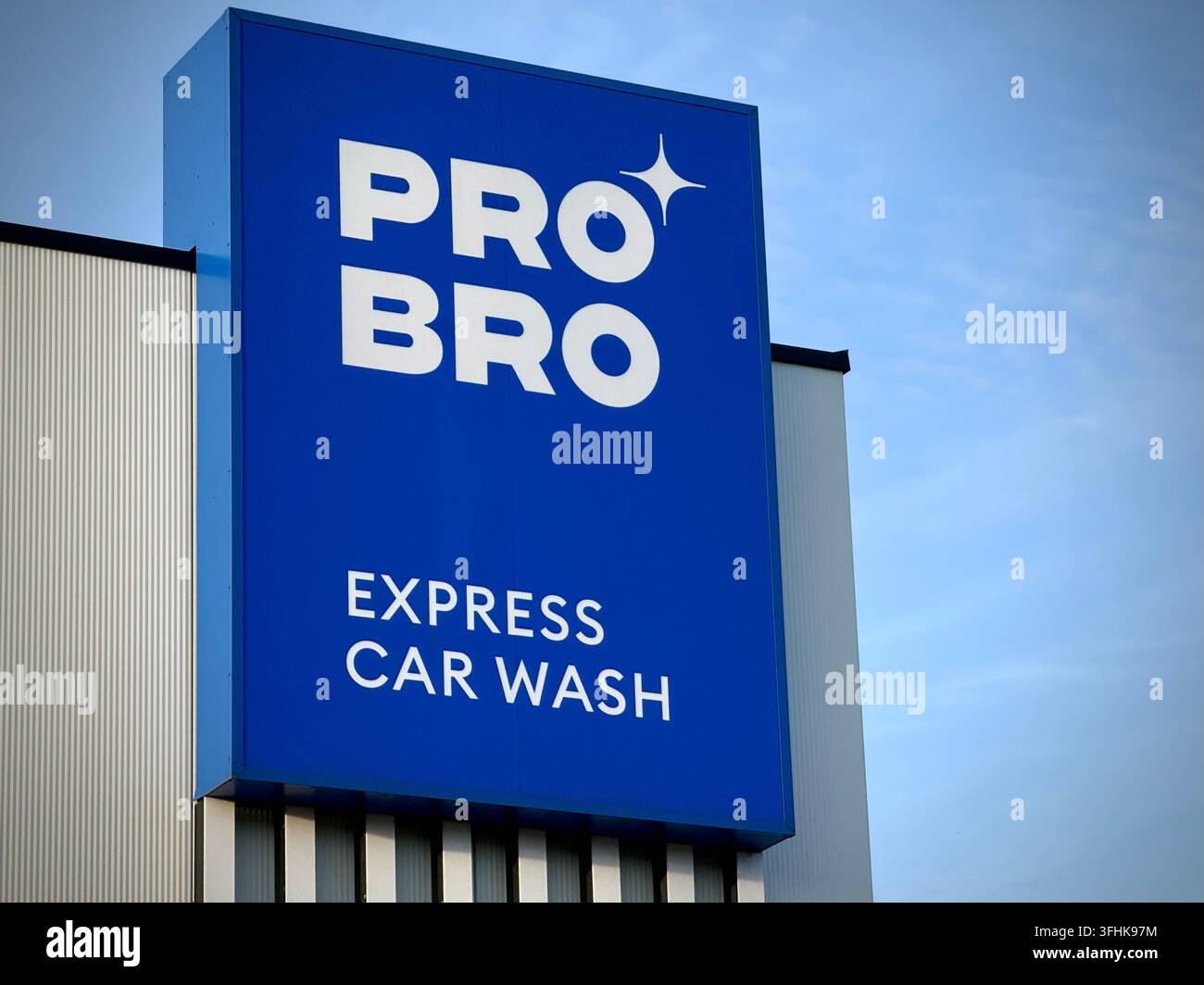 Blaues Werbeschild für PRO BRO Express Car Wash, ein beliebtes litauisches Franchise-Netzwerk für Fahrzeugreinigung, an einer modernen Gebäudefassade unter klarem Himmel Stockfoto