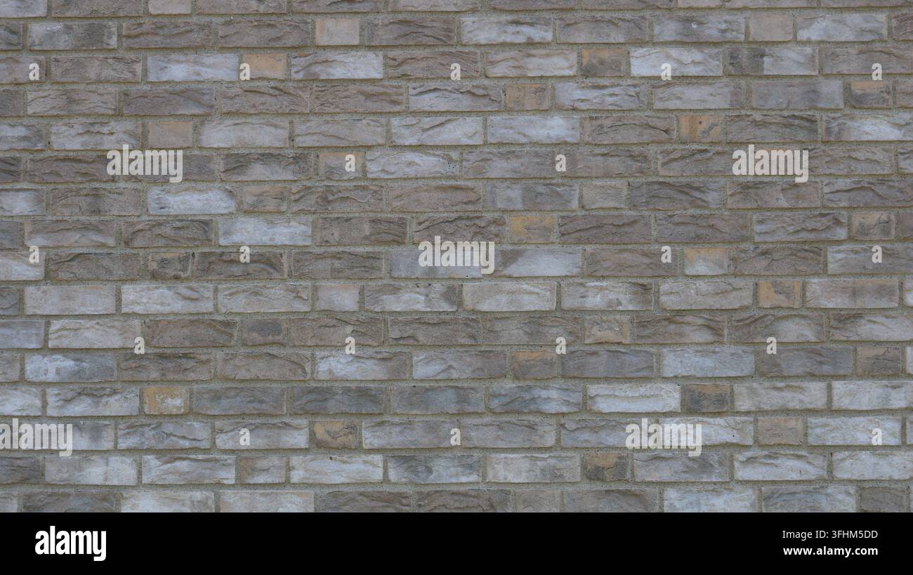 Ein Hintergrund aus texturierter grau-beiger Verkleidungsstein. Eine Makroaufnahme der glatten Textur von Kunstziegelmauern mit ungleichmäßiger Färbung. Perfekt für den Bau Stockfoto