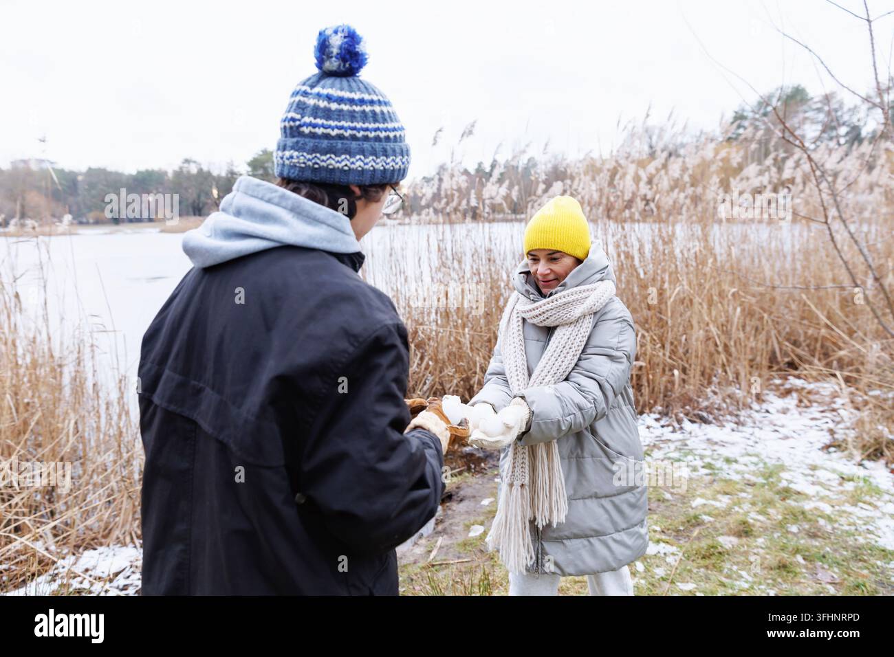 Spielerische Winterinteraktion zwischen Mutter und Teenager am See Stockfoto