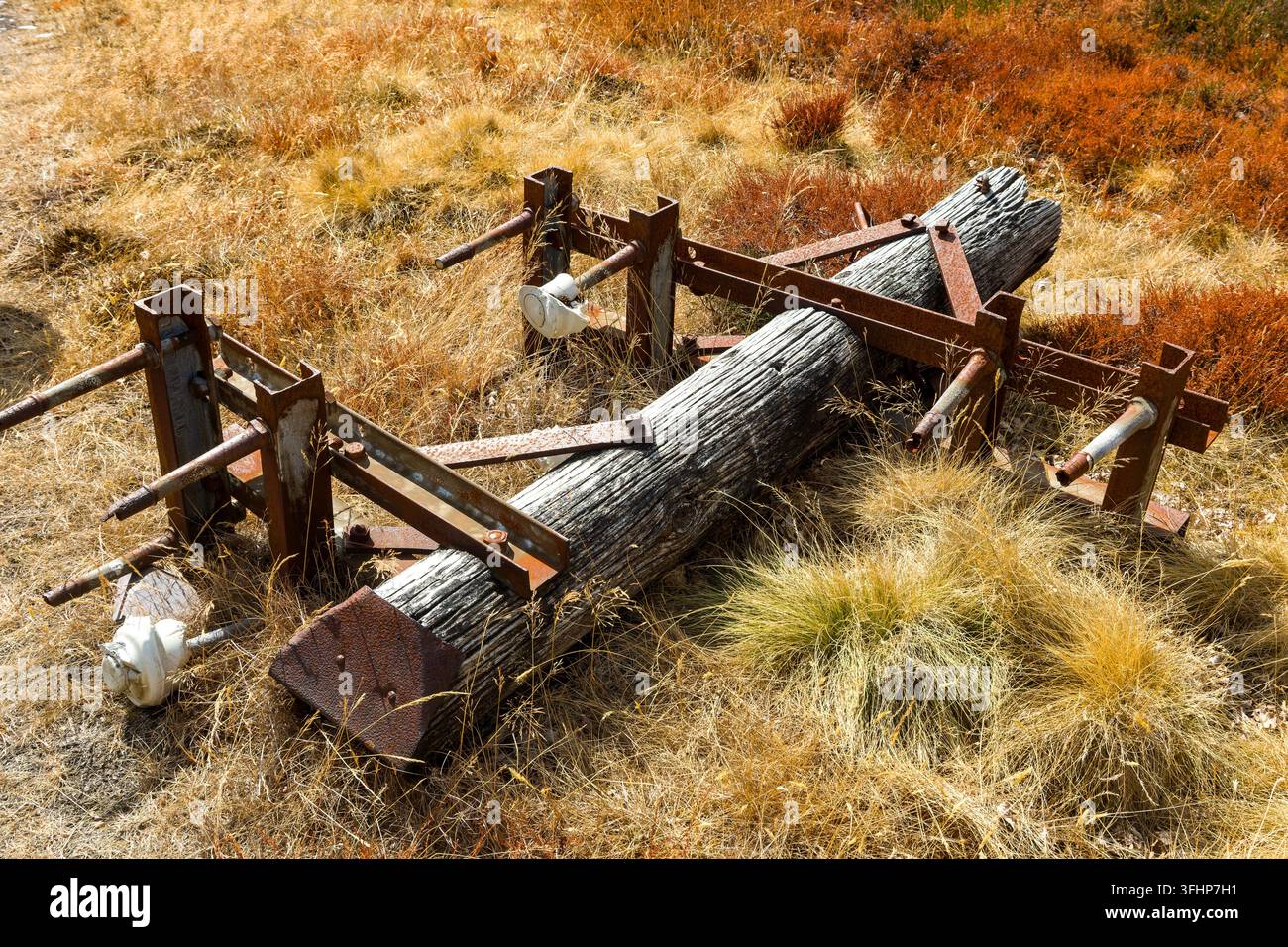 Gefallener hölzerner Strommast mit verrosteten Metallklammern, der auf Heidekraut und Gras ruht, vintage industrielle Ausrüstung, die auf offenem walisischem Moor verfallen ist Stockfoto