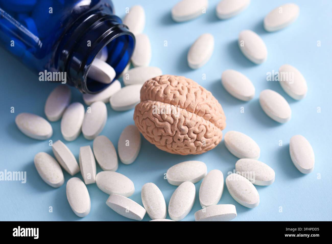 Hirnorgan-Modell zwischen weißen Medizintabletten und einer Medizinflasche. Medizinischer Hintergrund für die Behandlung von Gehirngesundheit, neurologischen Erkrankungen und psychischen Störungen. Stockfoto