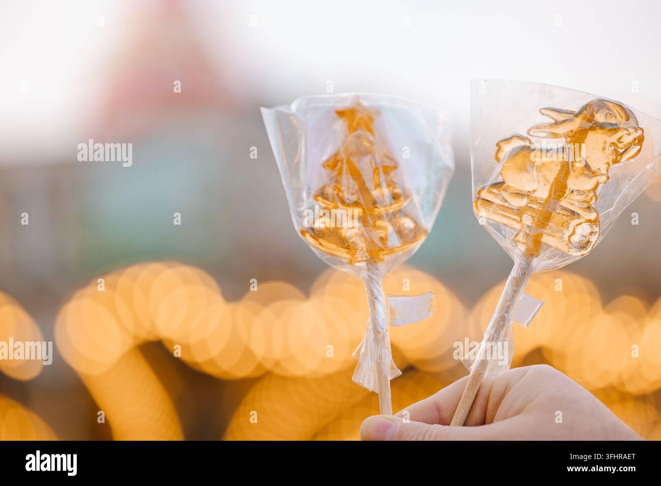 Hand, die weihnachtliche goldene Lutscher mit Stiel hält Stockfoto