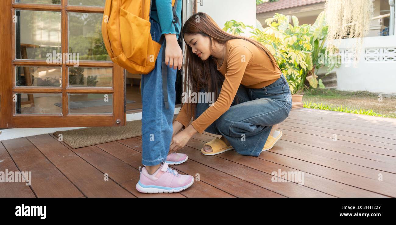 Vorbereitung auf die Schule. Eine Mutter, die ihrer Tochter Schnürsenkel vor der Schule fesselt. Stockfoto