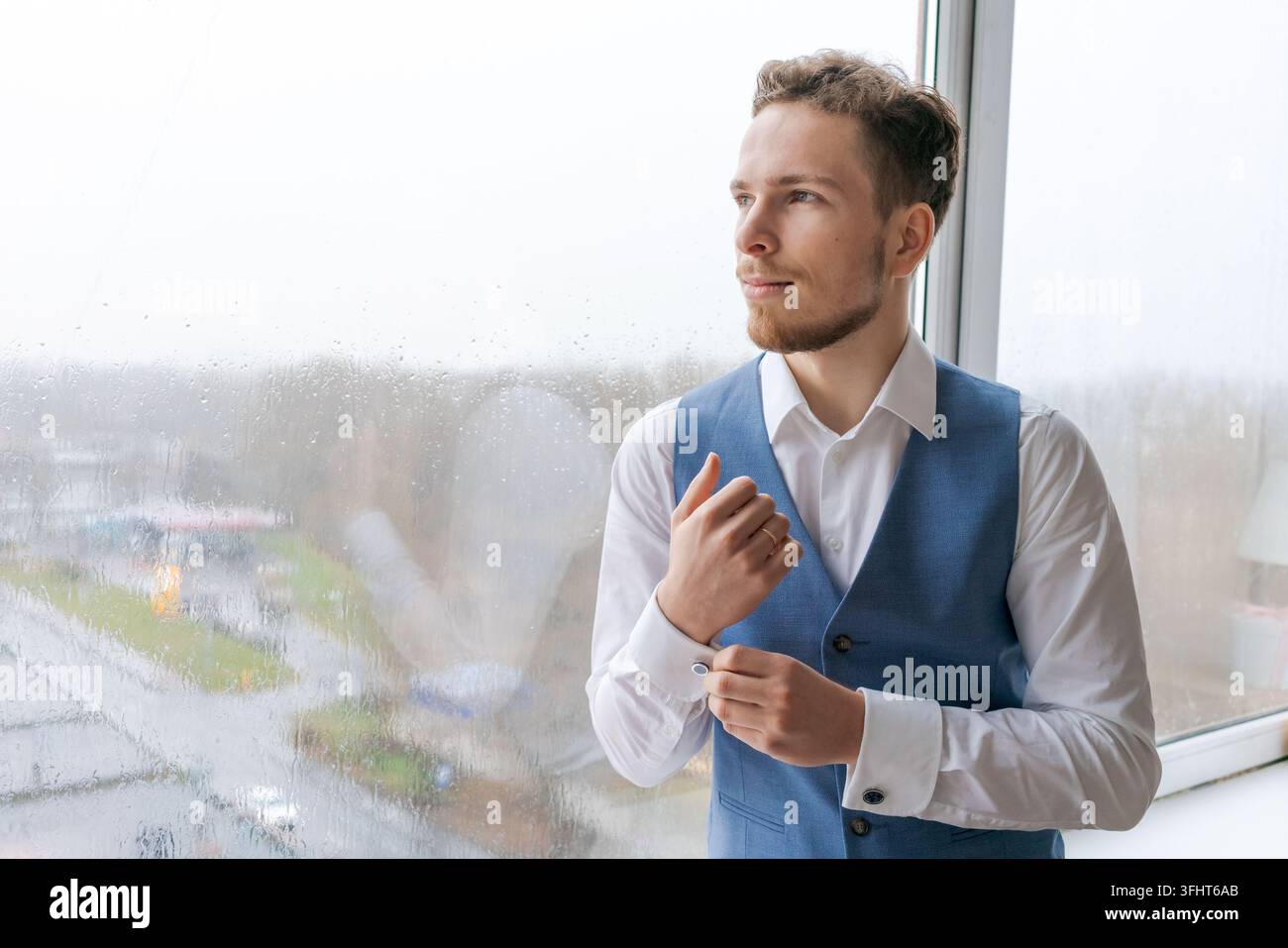 Porträt eines arroganten, scharf gekleideten Mannes in blauem Anzug, der einen Knopf korrigiert Stockfoto