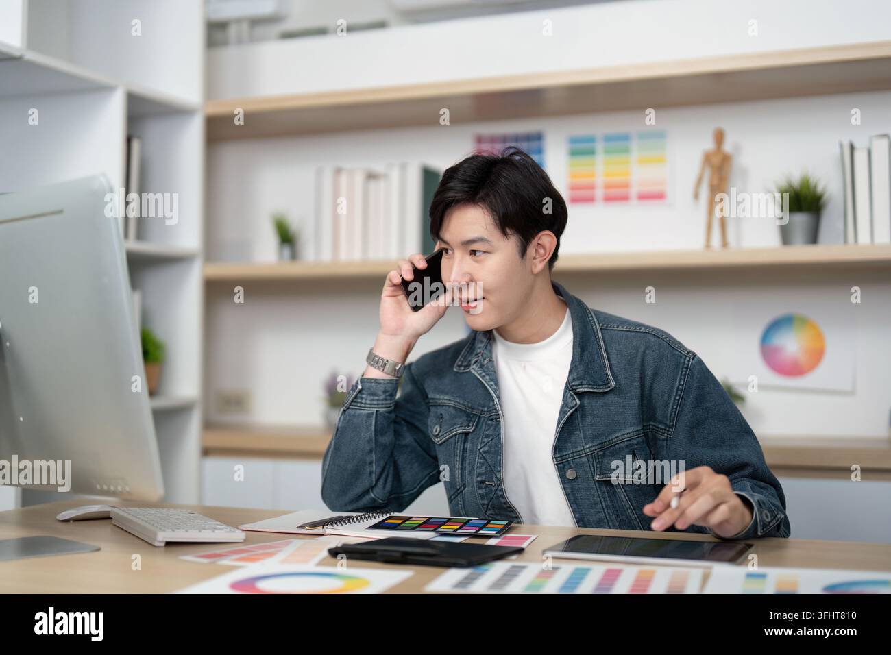 Design Communication: Young Professional on Phone in Creative Workspace Stockfoto