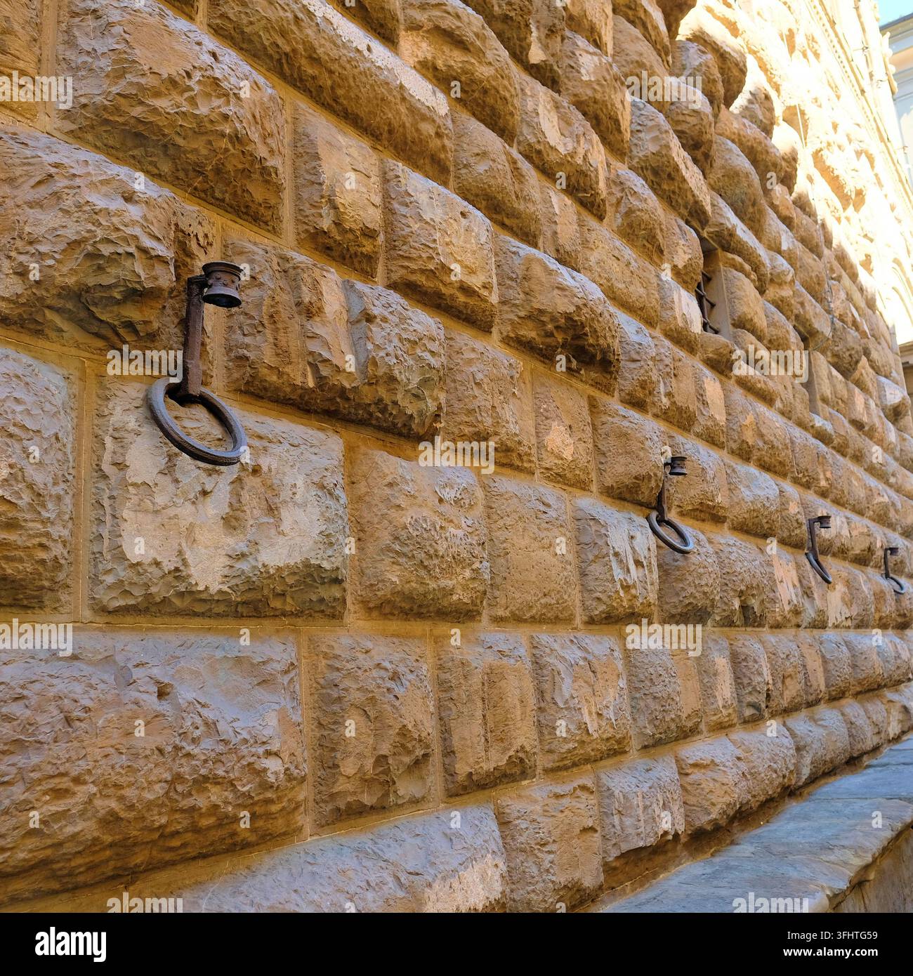Steinfassade mit Eisenringen an der Wand des Palazzo Medici Riccardi in Florenz, Italien, Fassadenringe, die verwendet wurden, um Pferde zu binden oder Fackeln, Banner zu halten. Stockfoto