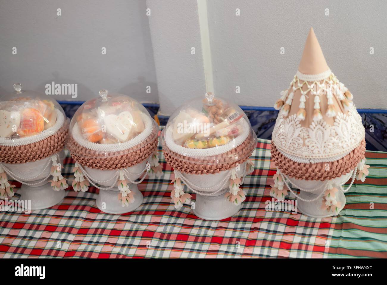Traditionelle thailändische zeremonielle Behälter und Opferungsschalen auf einer gemusterten Matte Stockfoto