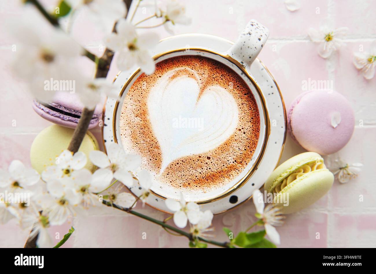 Kaffee mit herzförmigem Muster und süßen Macaron-Desserts Stockfoto